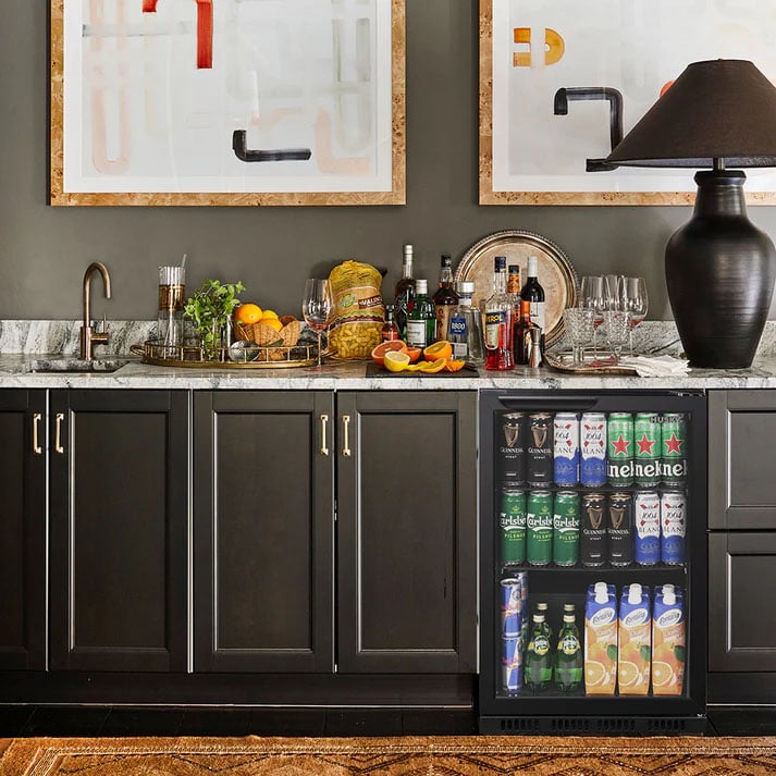 Drinks chiller integrated into a dark bar cabinet with a marble countertop