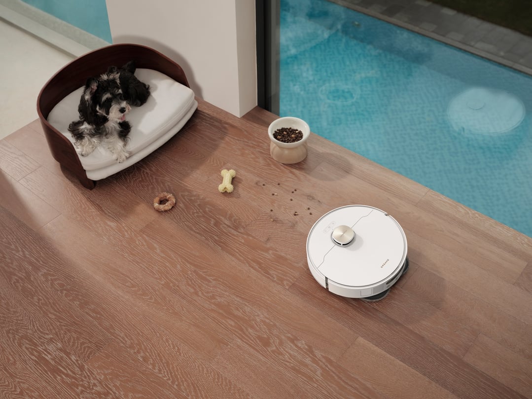 White robot vacuum and mop on a wooden floor with a dog and dog food
