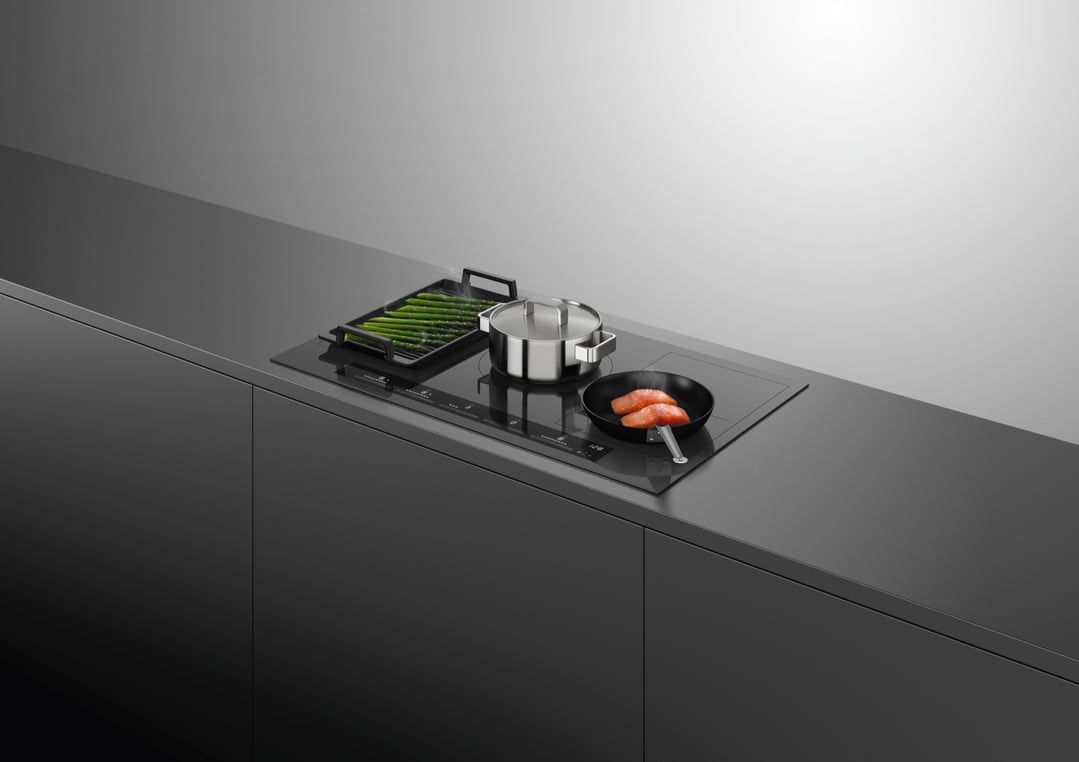 Induction cooktop with asparagus, pot, and salmon cooking in a modern kitchen