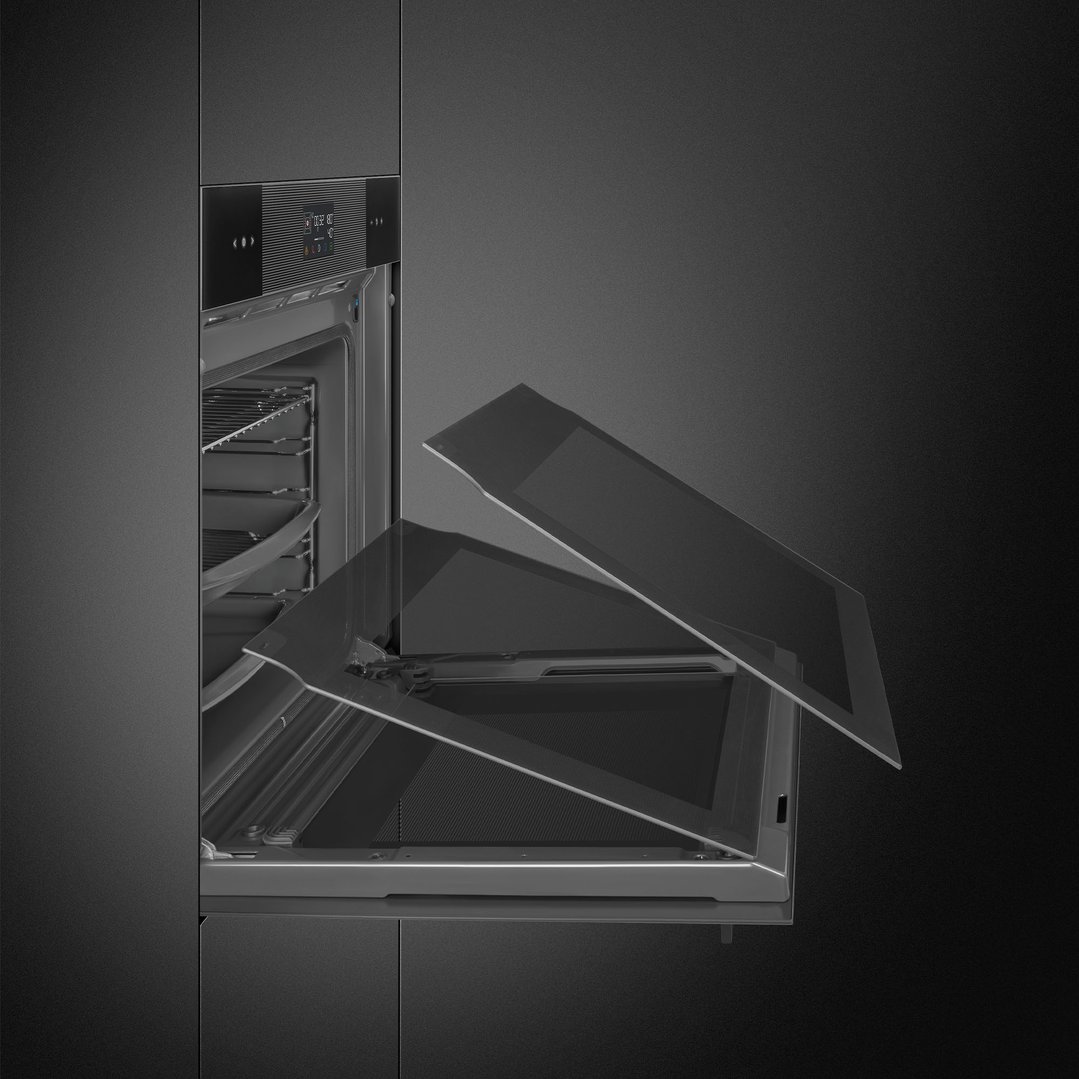 A black Linea oven with its door partially open in a dark kitchen