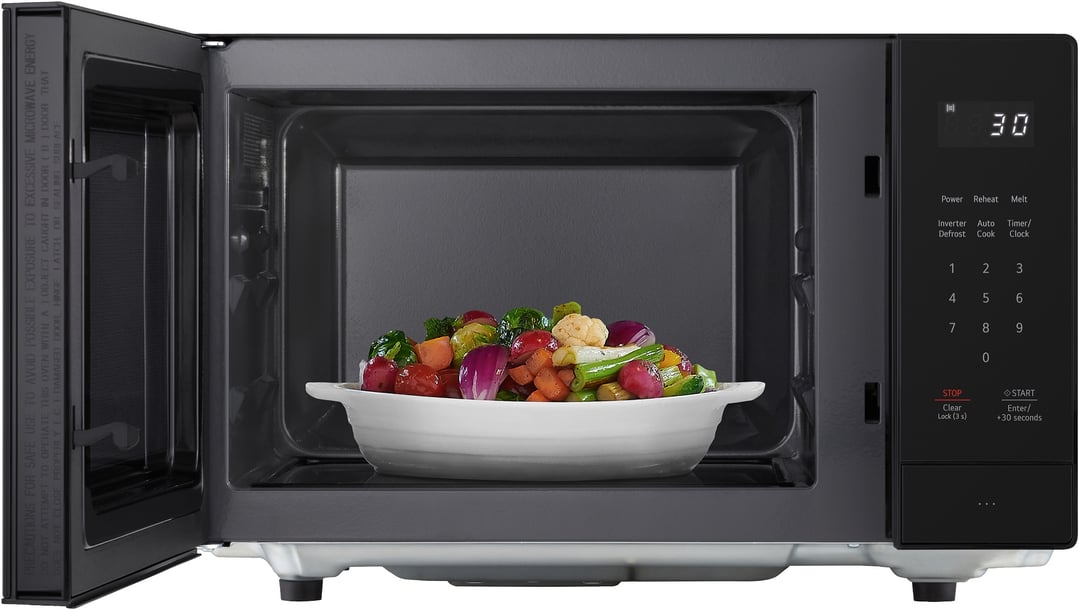 Black microwave with door open, bowl of vegetables inside