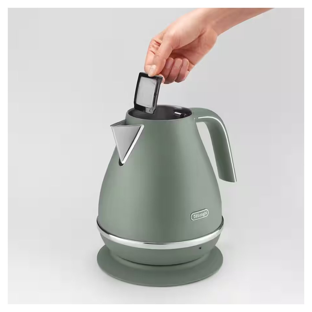 Hand removing the filter from a green kettle on a light background