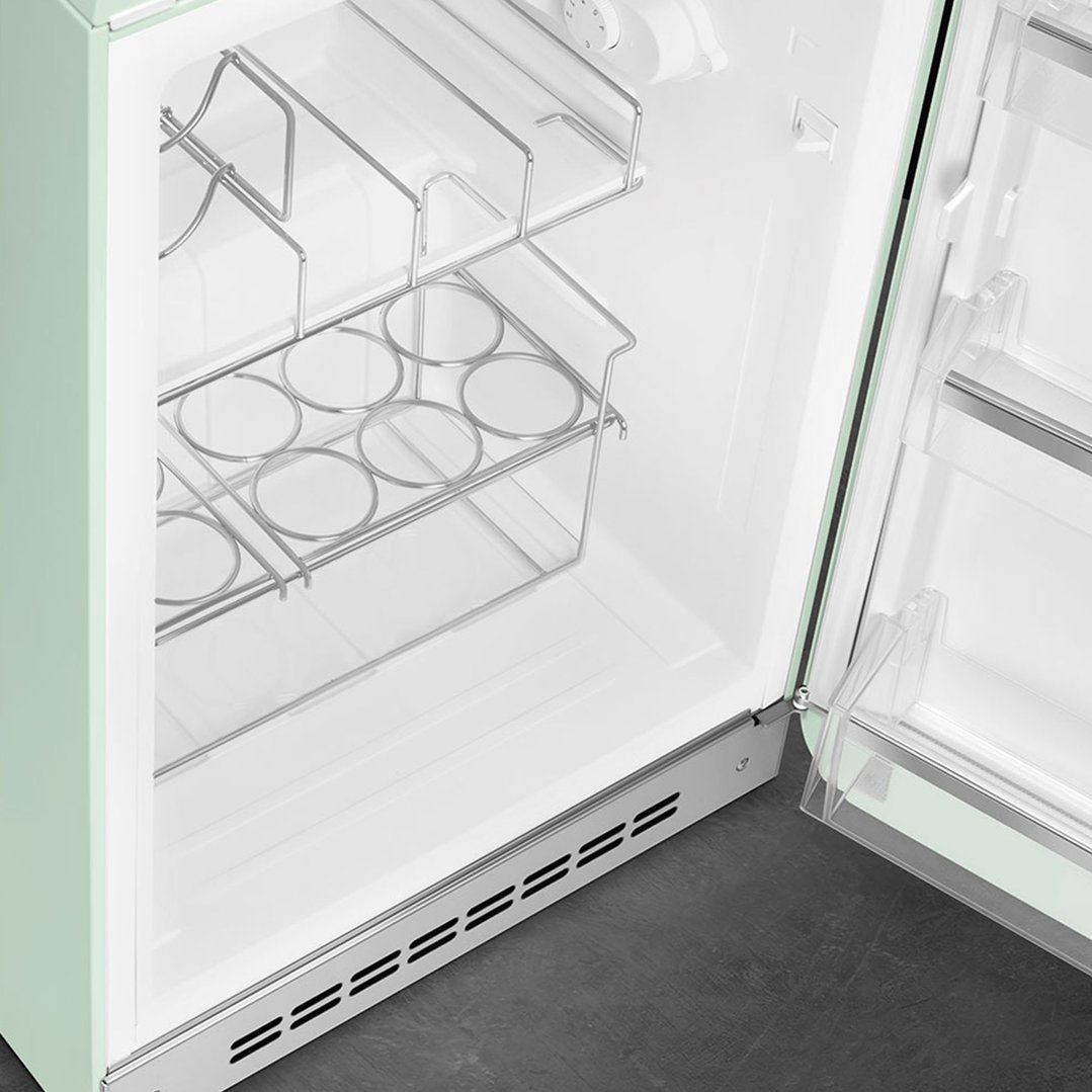 Open pastel green Smeg refrigerator showing interior shelves and door storage