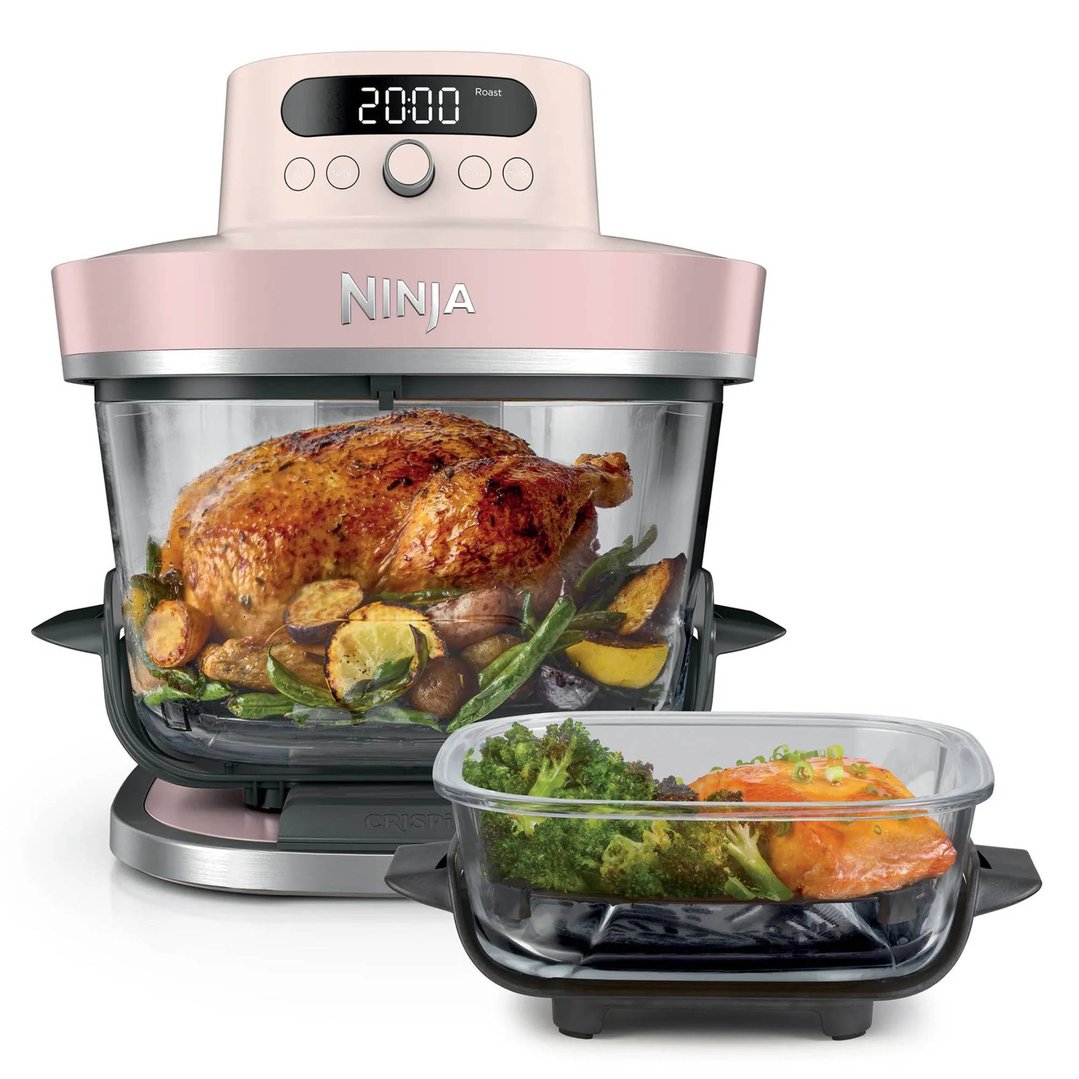 Pink Ninja air fryer with a whole roasted chicken and vegetables inside
