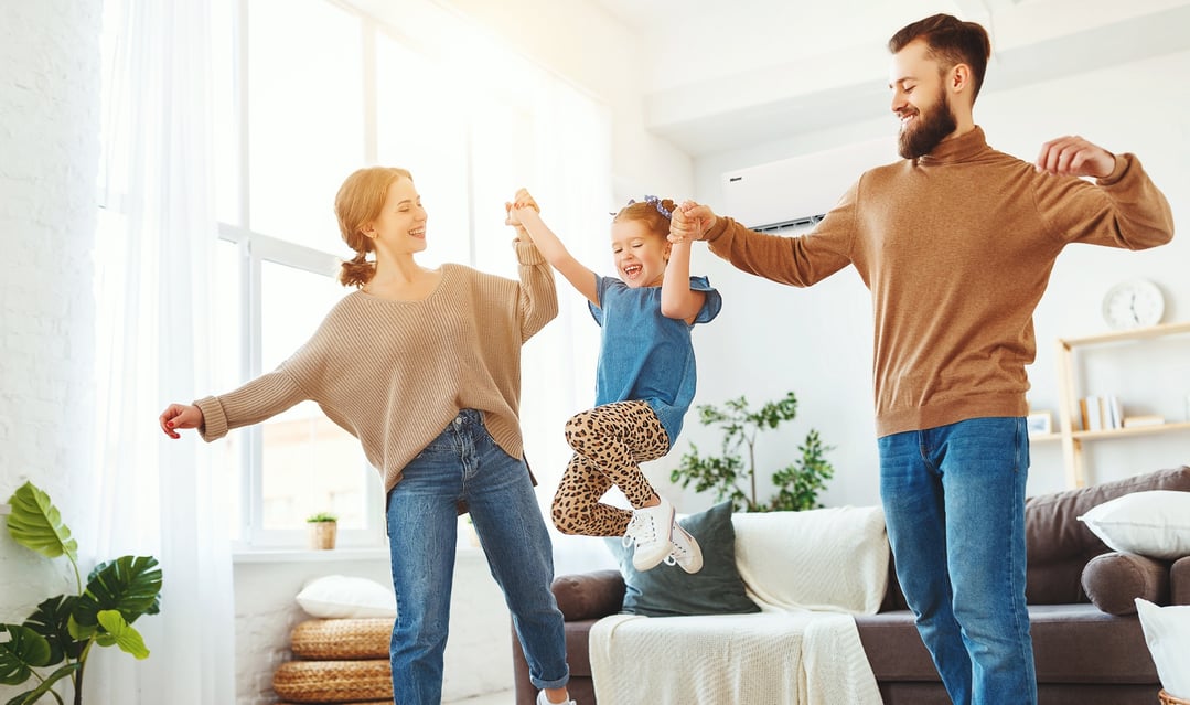 Family playing in a living room with a Hisense air conditioner on the wall