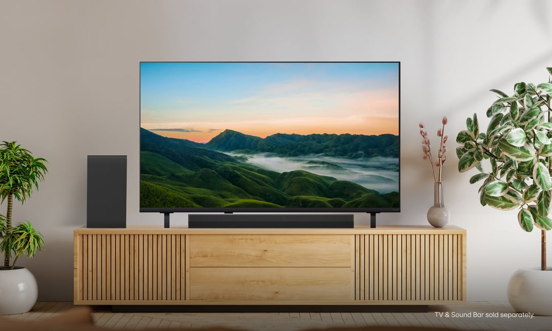 A TV on a wooden stand with a soundbar and subwoofer in a living room