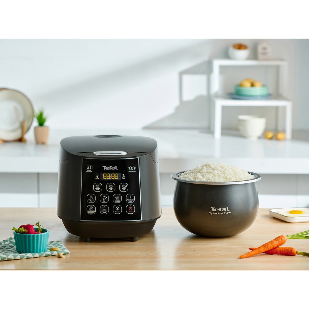 Tefal rice cooker and spherical bowl with rice on a wooden kitchen counter