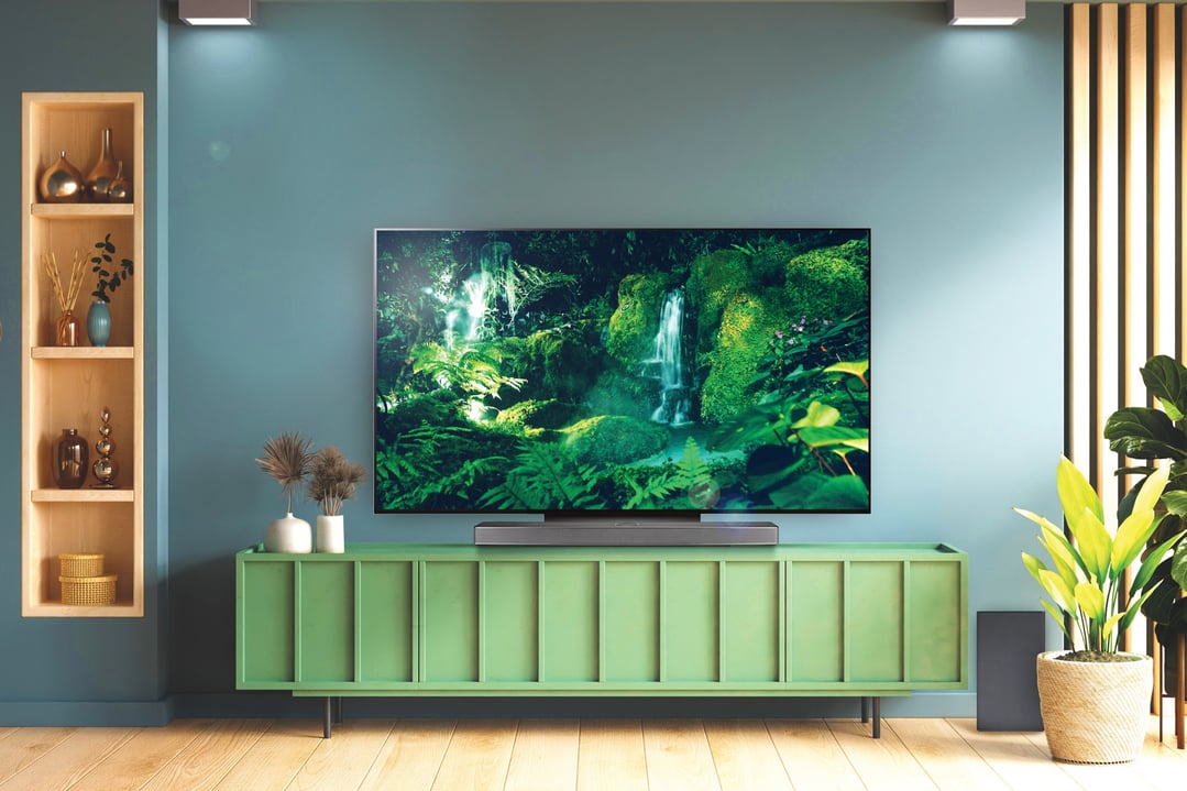 LG OLED Evo C3 4K UHD Smart TV on a green cabinet in a living room