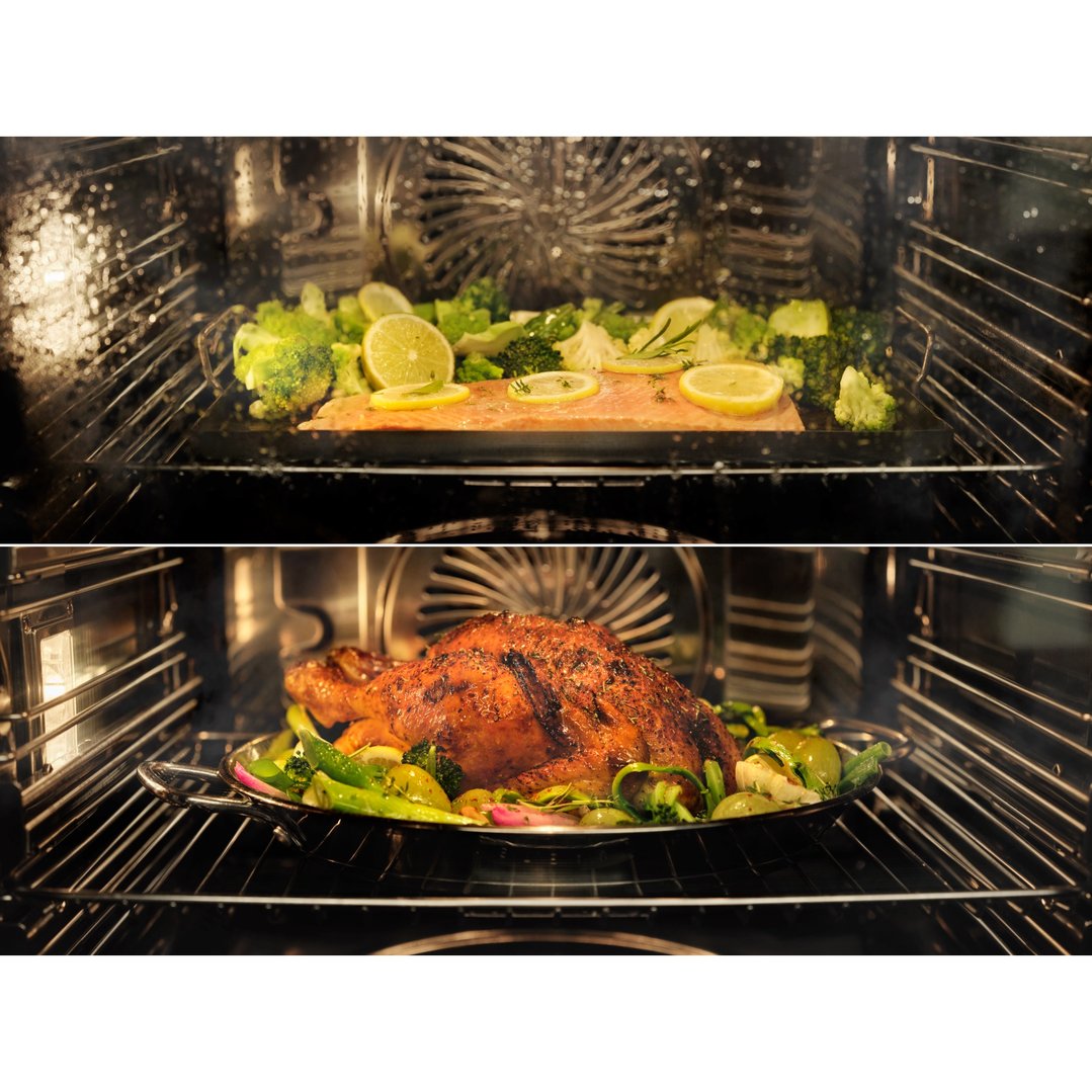 Salmon and chicken cooking inside an oven with vegetables