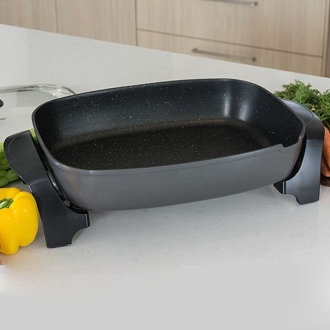 Electric frypan on a kitchen counter with vegetables in the background