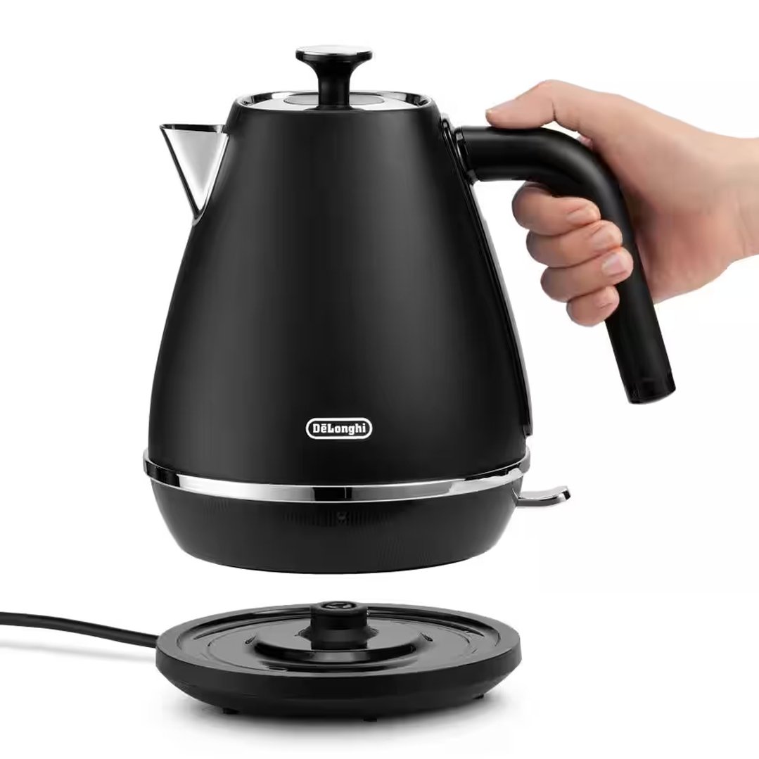 Hand holding a black DELONGHI kettle above its base