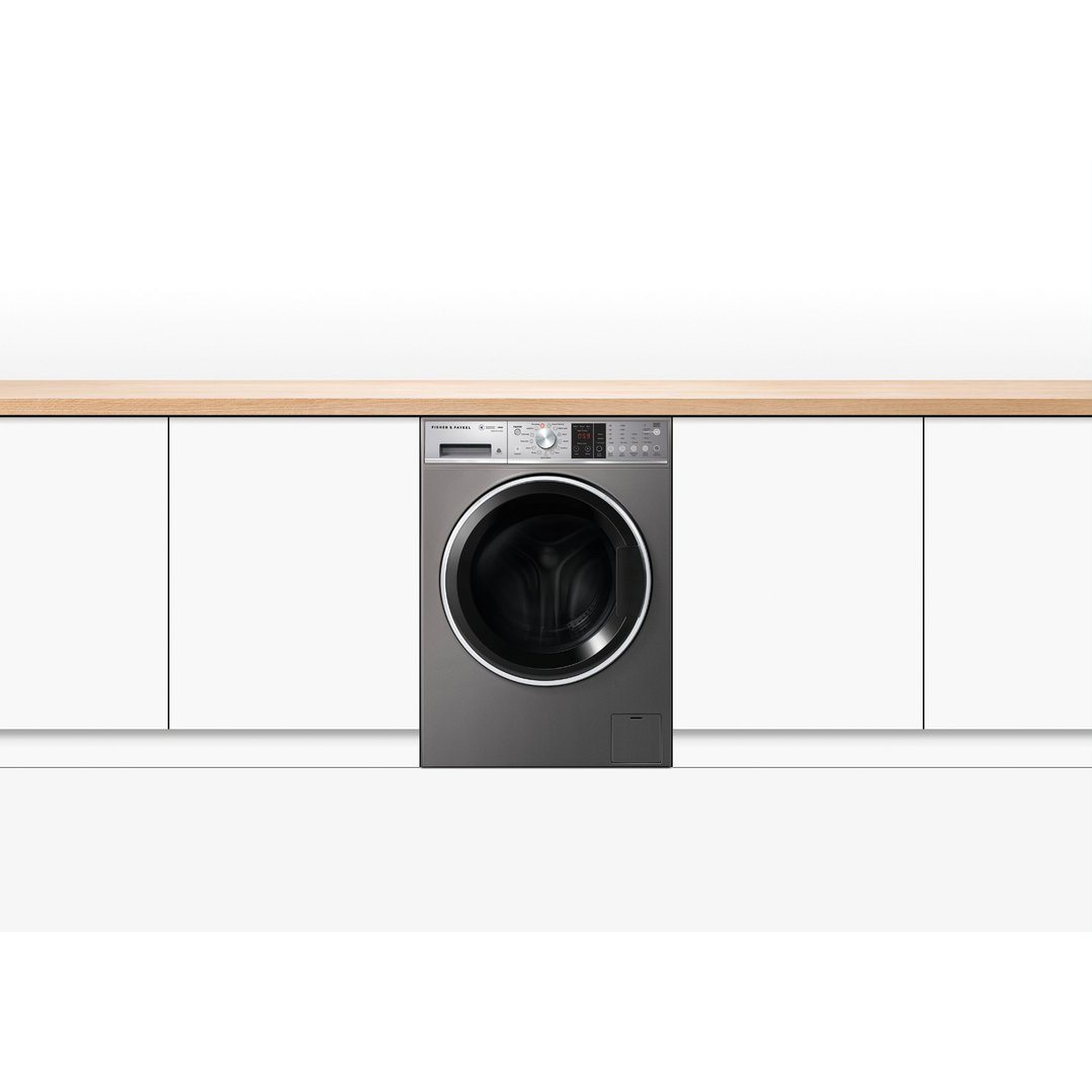 Front load washing machine integrated into white cabinetry with a wooden countertop