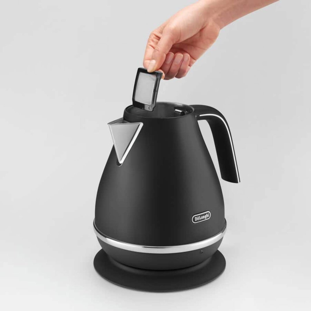 Hand opening the lid of a black DeLonghi kettle