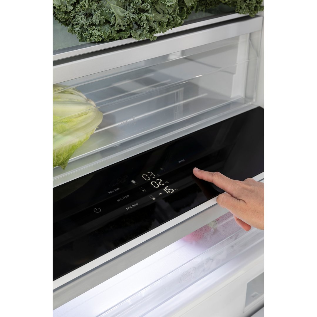 Hand adjusting the digital temperature display inside a bottom mount fridge