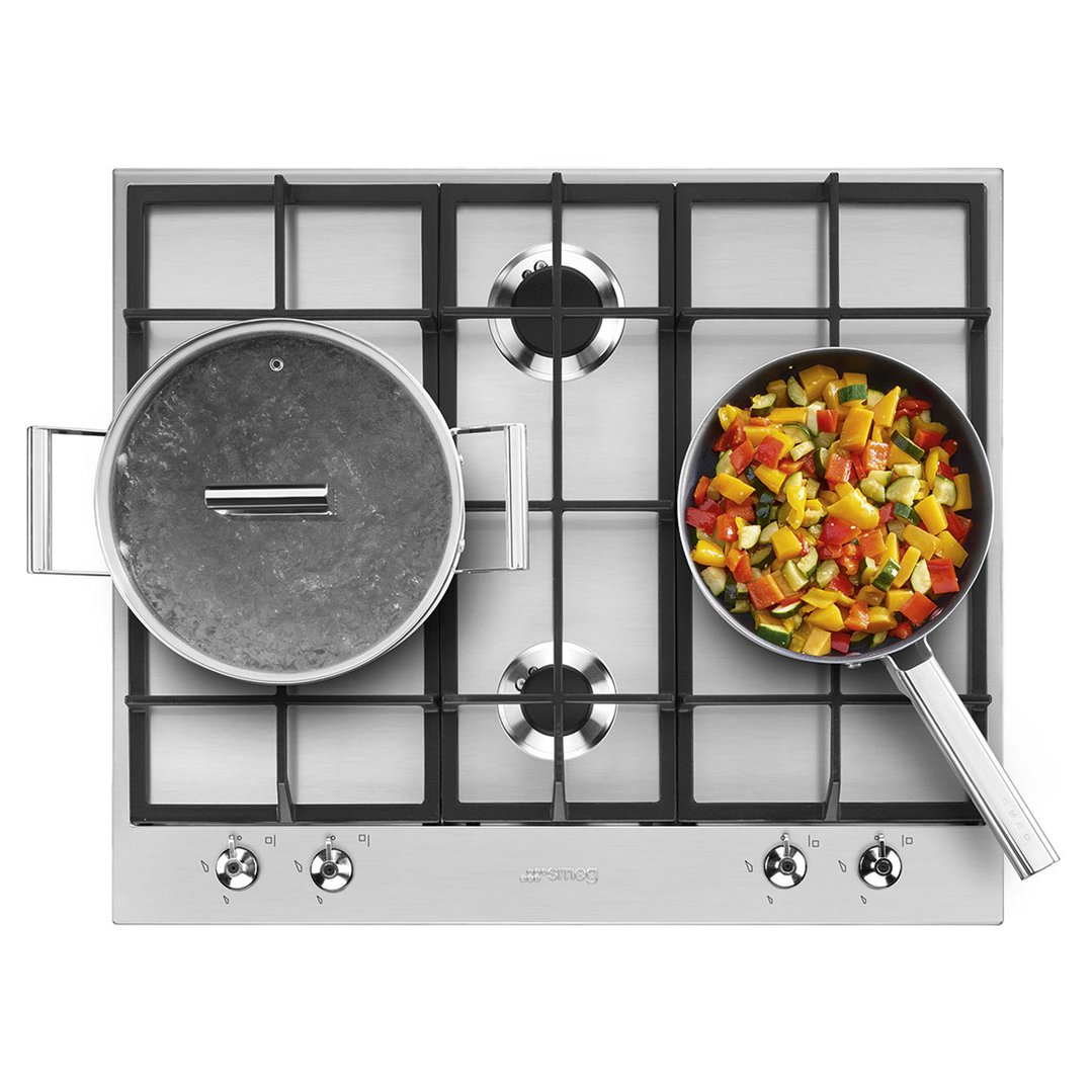 Overhead view of a Smeg cooktop with a pot and a pan of vegetables