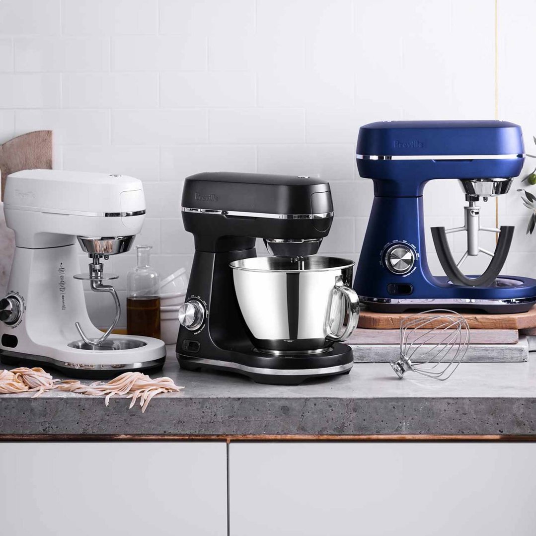 Three Breville food mixers in white, black, and blue on a kitchen counter