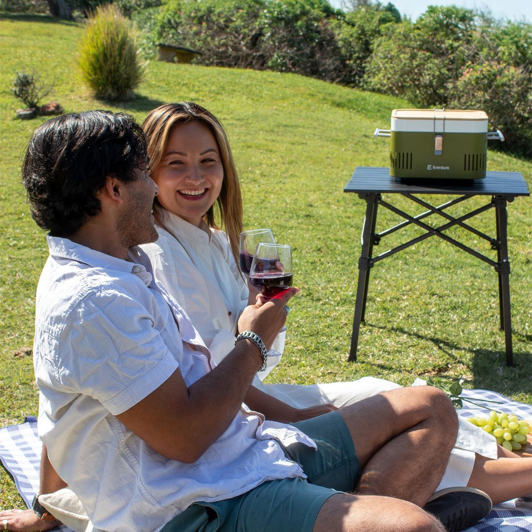 Couple enjoying a picnic with a portable charcoal BBQ on a table