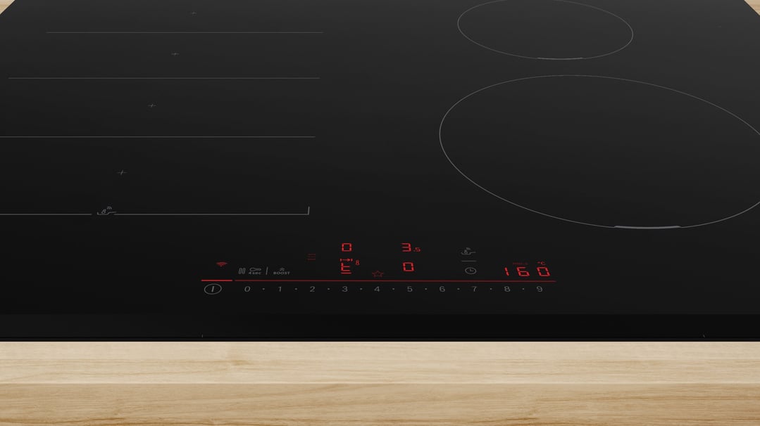 Black induction cooktop with digital controls on a light wooden countertop