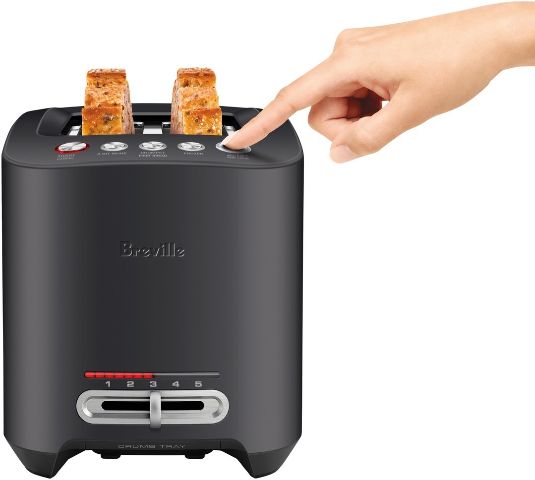 Hand pressing button on black Breville toaster with toast slices inside