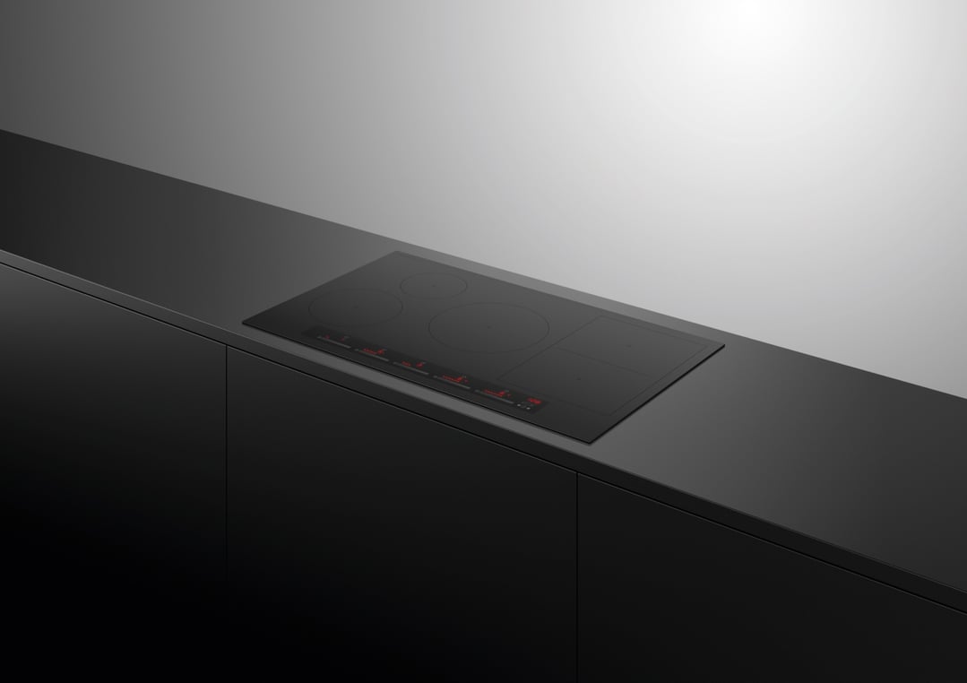 Black induction cooktop integrated into a dark kitchen countertop and cabinetry