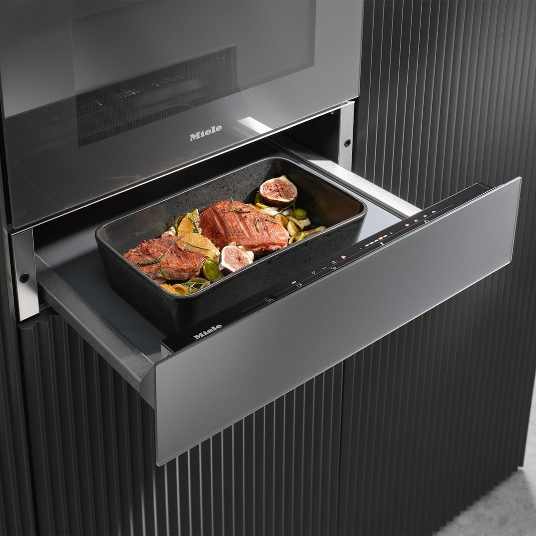 Gourmet warming drawer with food in a baking dish, pulled out from under an oven