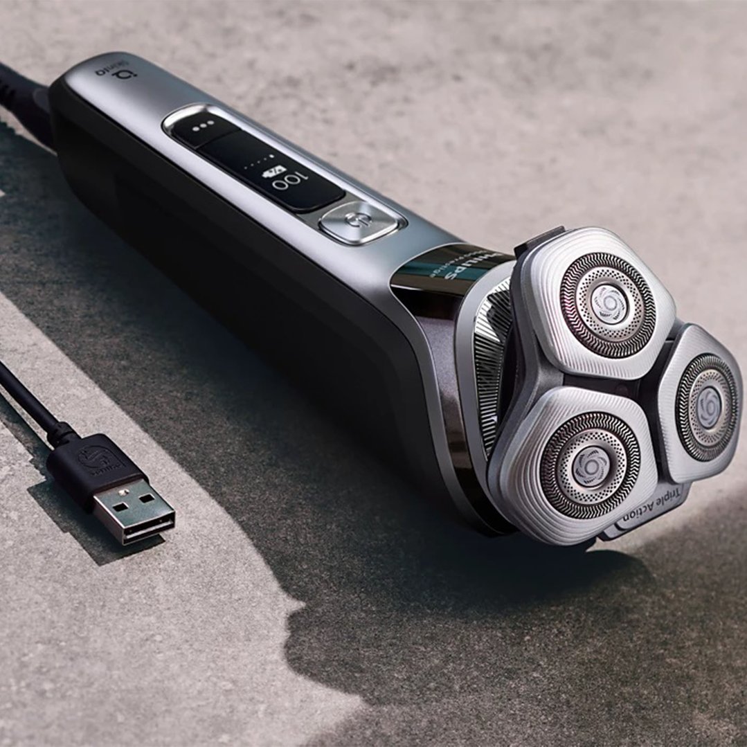 Philips electric shaver with USB cable on a textured grey surface