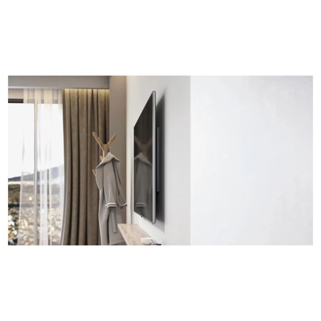 A wall-mounted TV in a room with a coat rack and curtains