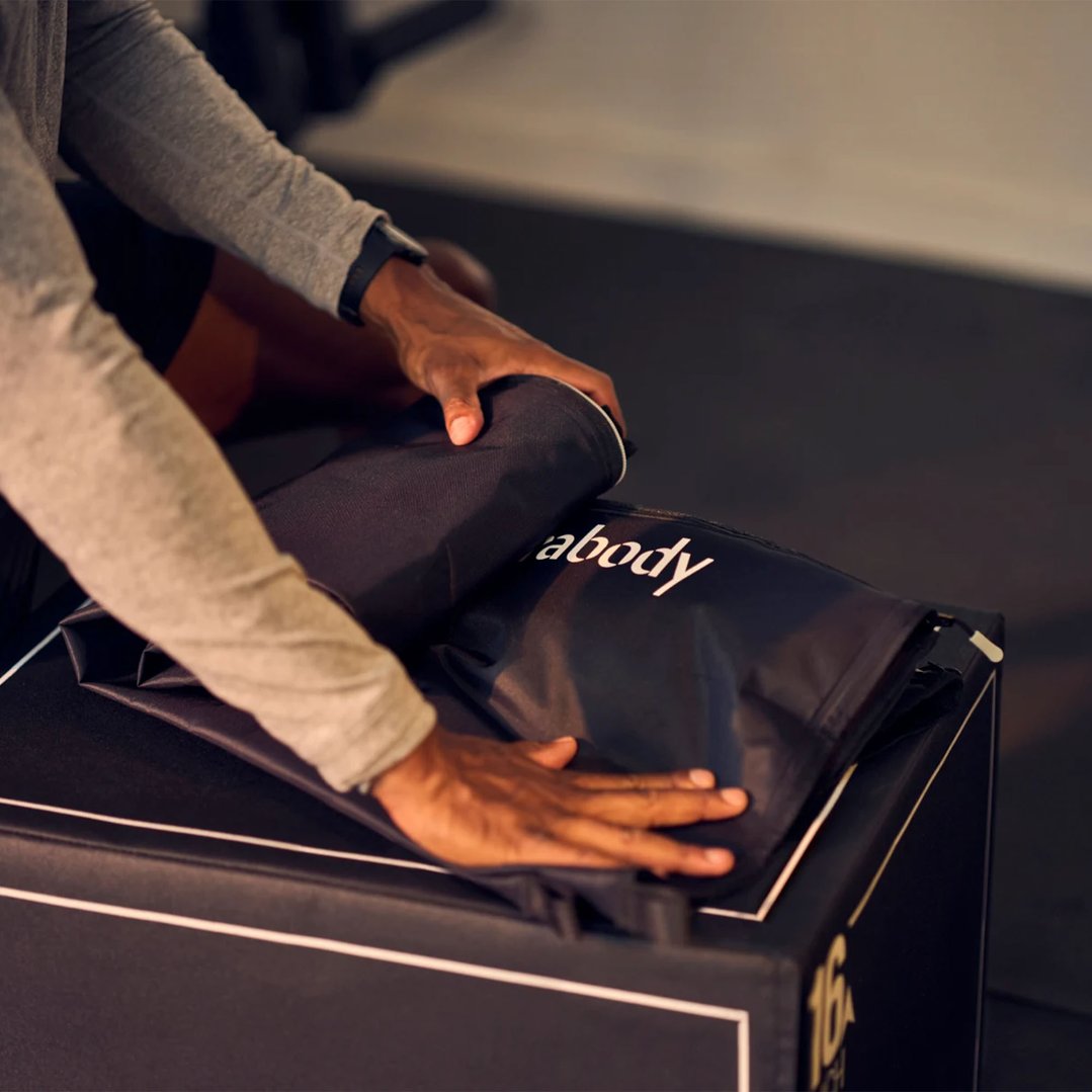 Person's hands folding a black massager with white text on a dark surface