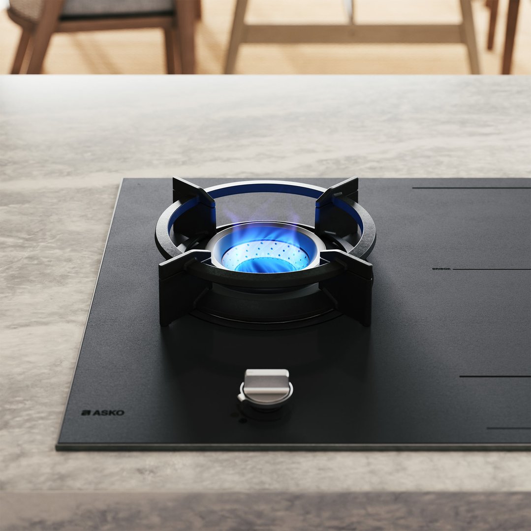 A black gas and induction cooktop with a blue flame on a grey countertop