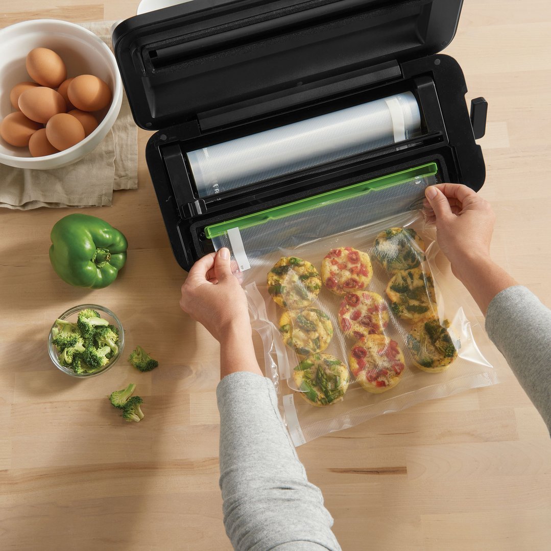 Hands sealing a bag of egg bites with a Cut & Seal Vacuum Sealer