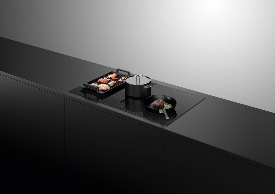 Induction cooktop with a pot, a pan with steak, and a grill with chicken