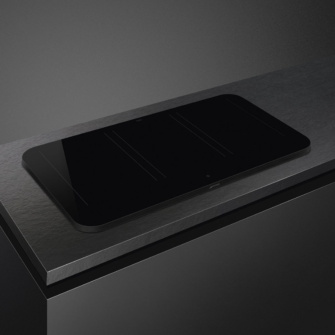 Black Smeg induction cooktop integrated into a dark countertop in a modern kitchen