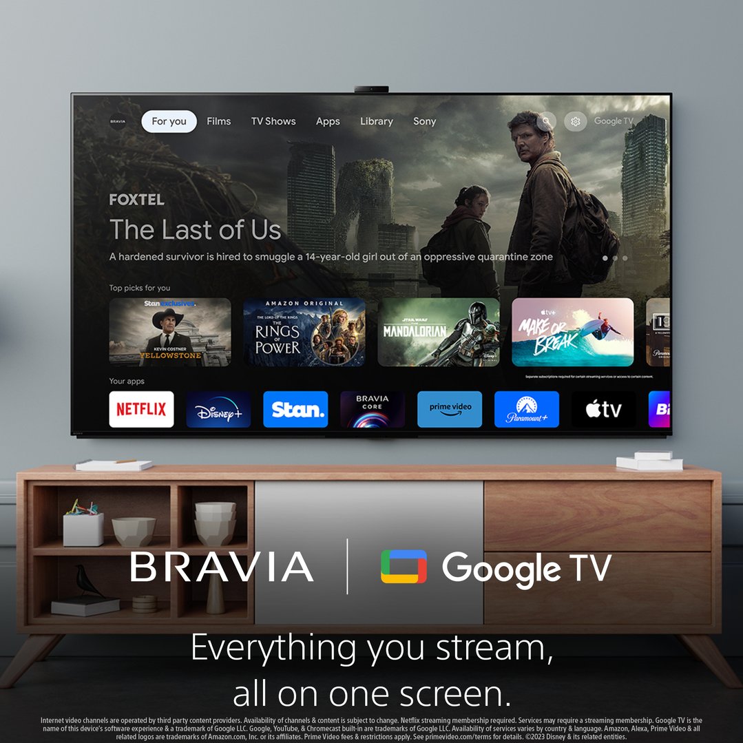 Sony Bravia TV on a wooden media console displaying Google TV interface