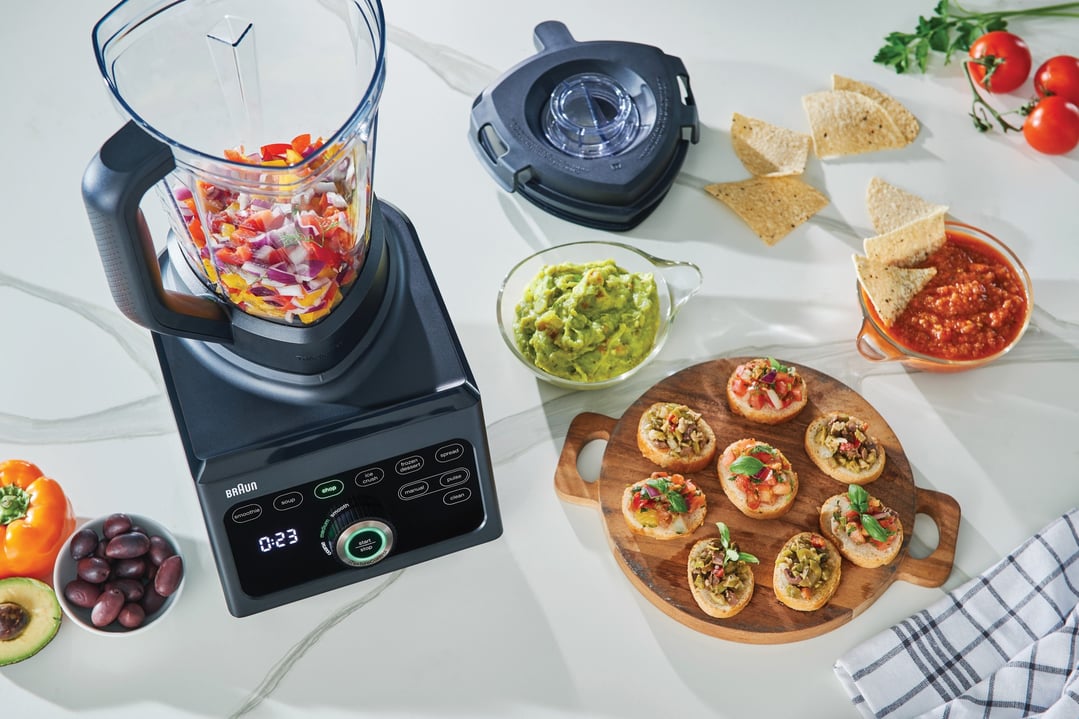 Braun PowerBlend 9 Jug Blender chopping vegetables on a kitchen counter with snacks