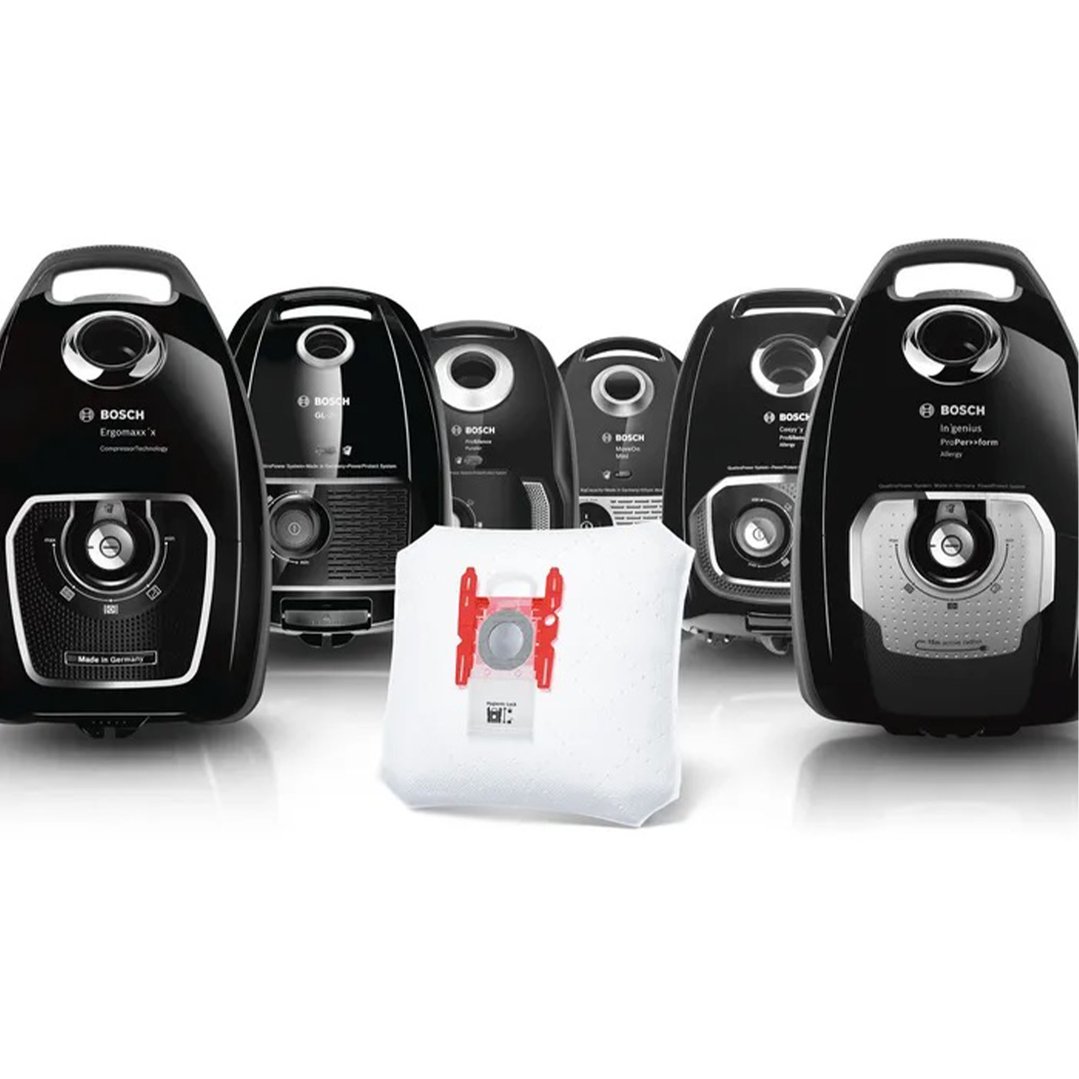 A white vacuum cleaner dustbag in front of several black vacuum cleaners