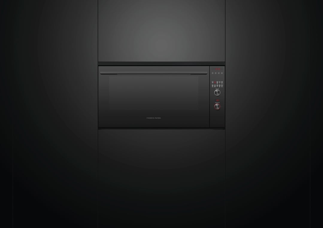 A black built-in oven with a digital display in a dark kitchen