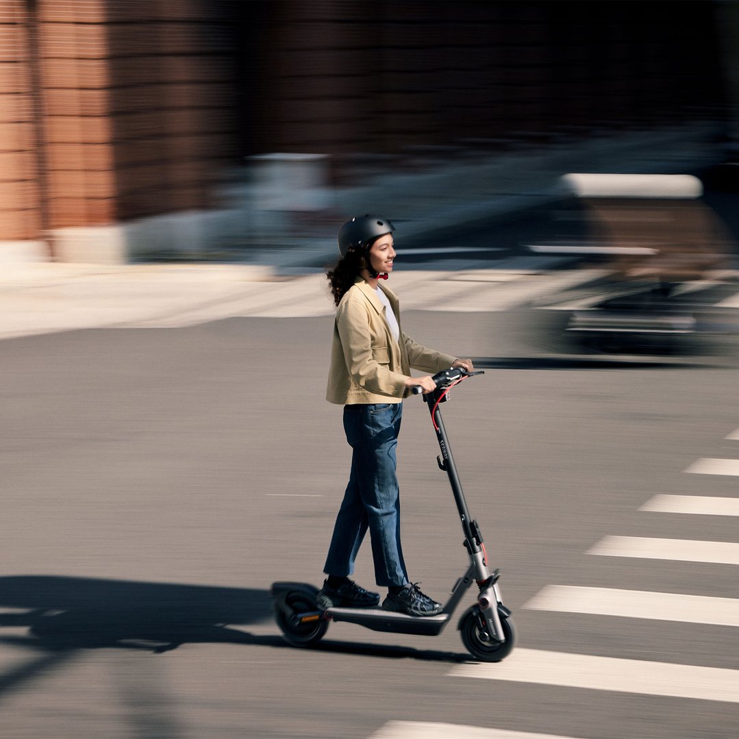 Woman in a helmet riding a Segway electric scooter on a city street