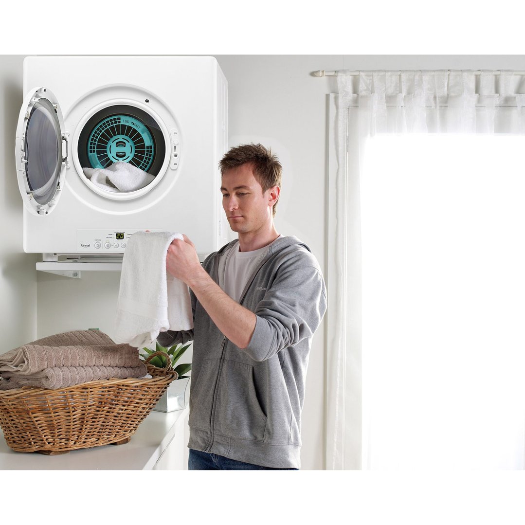 Man loading a white towel into the Rinnai dryer in a laundry room