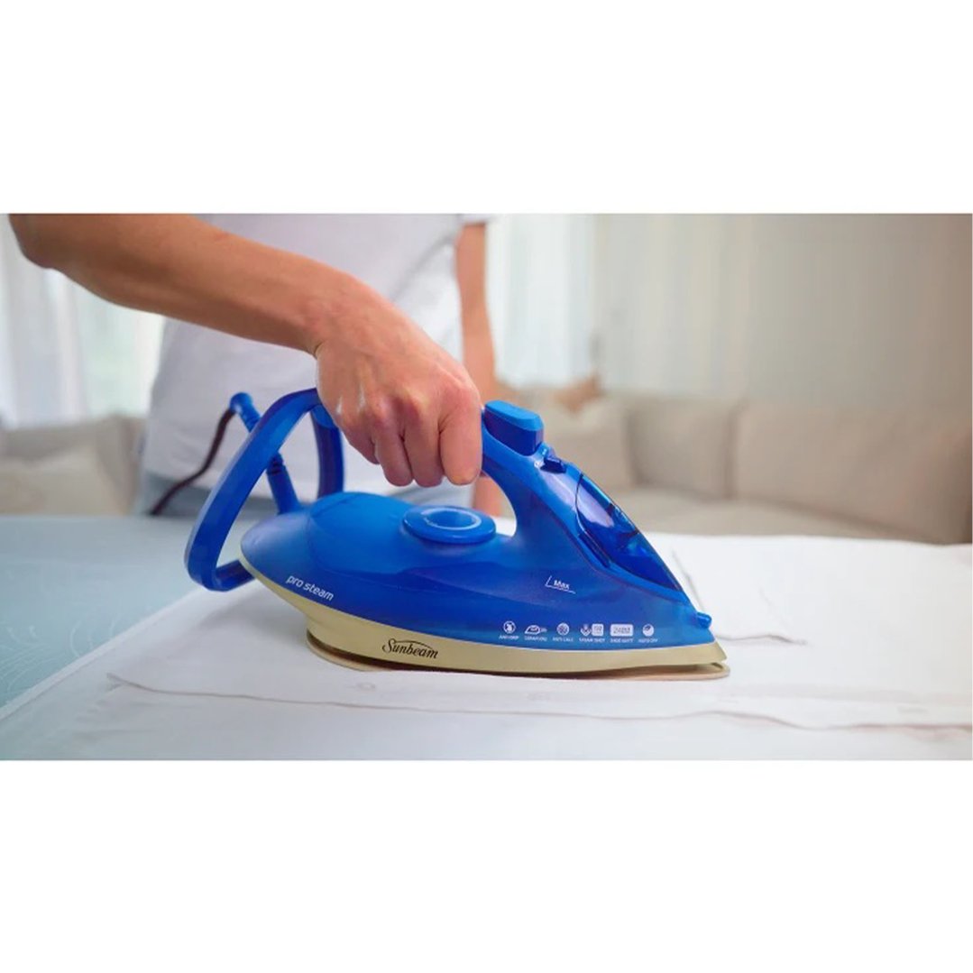 Person's hand holding a blue iron on a white garment
