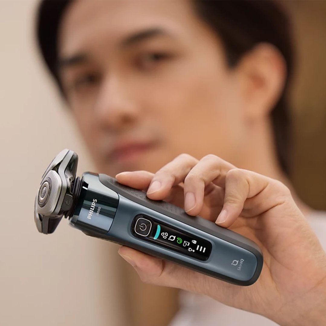 Man holding a Philips electric shaver with SkinIQ in his right hand