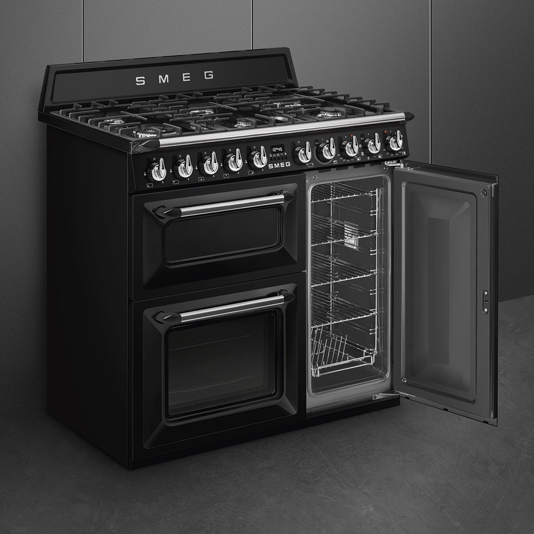 Black freestanding dual fuel oven/stove with open door in a dark kitchen