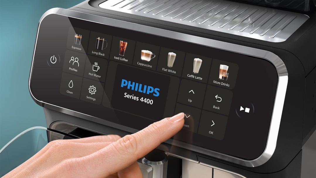 A hand interacting with the touchscreen display of a Philips Series 4400 espresso machine