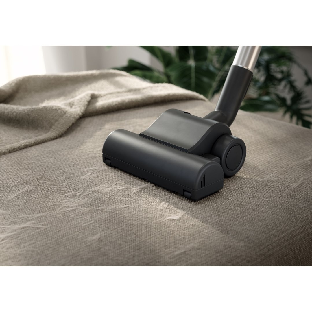 Vacuum cleaner head cleaning a light brown fabric sofa in a living room