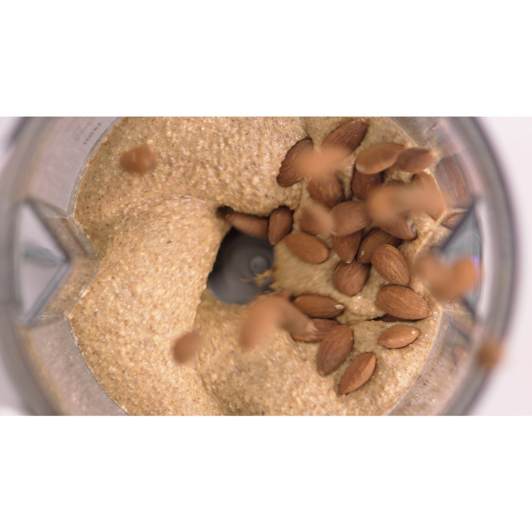 Overhead view of almonds being blended into nut butter in a blender