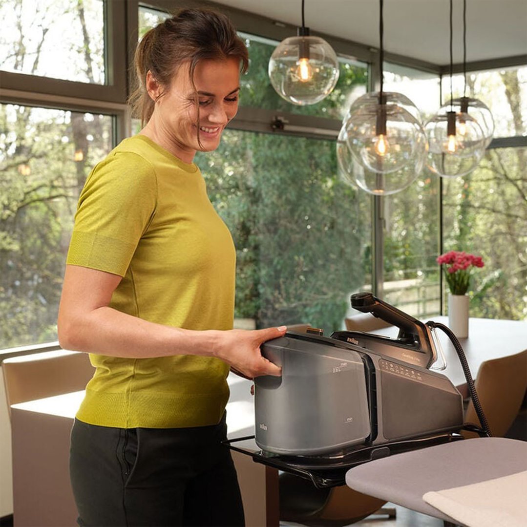 Woman smiling while placing the water tank into a steam generator iron