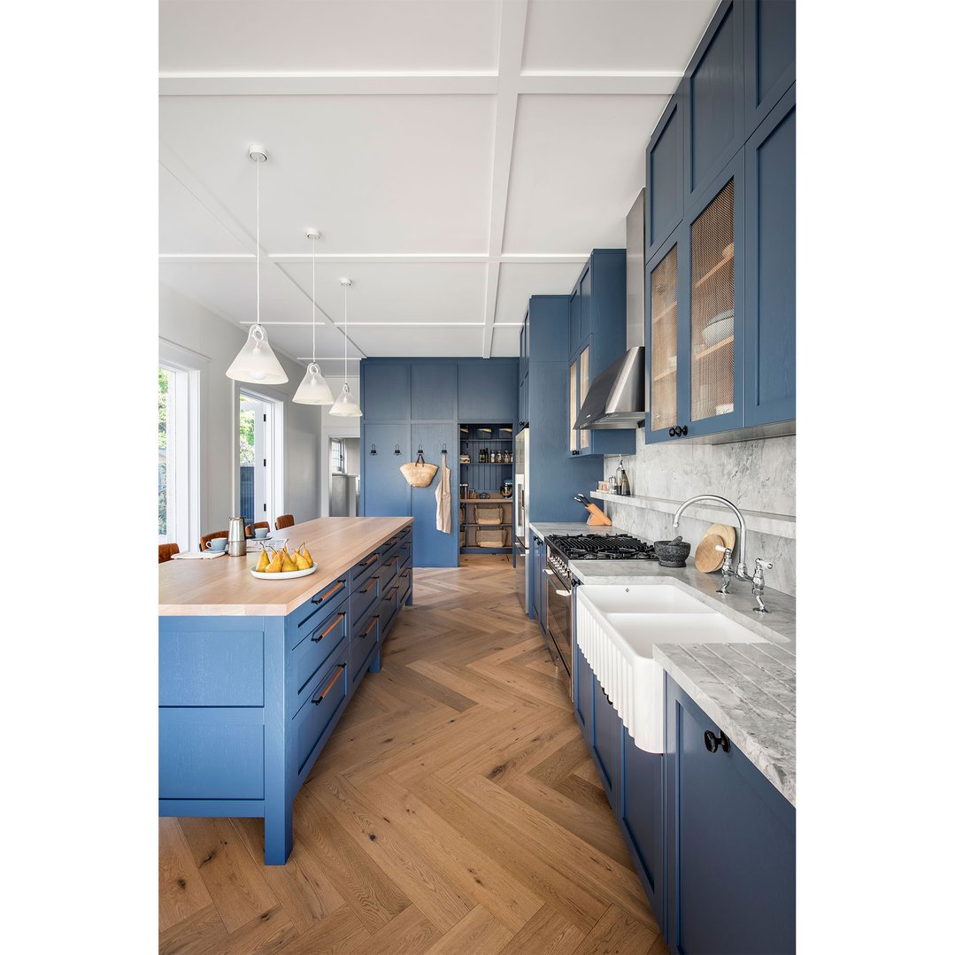Double bowl fireclay butler sink in a blue kitchen with wooden island