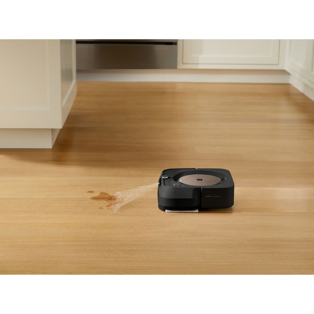 Black robot mop cleaning a spill on a wooden floor in a kitchen
