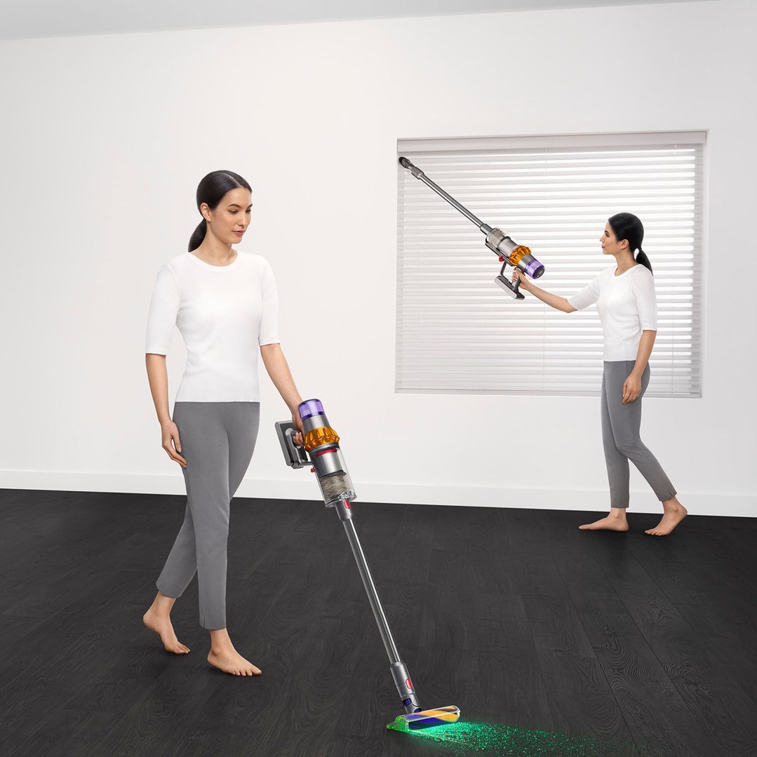 Two women using Dyson handStickVacuums to clean a room with dark floors