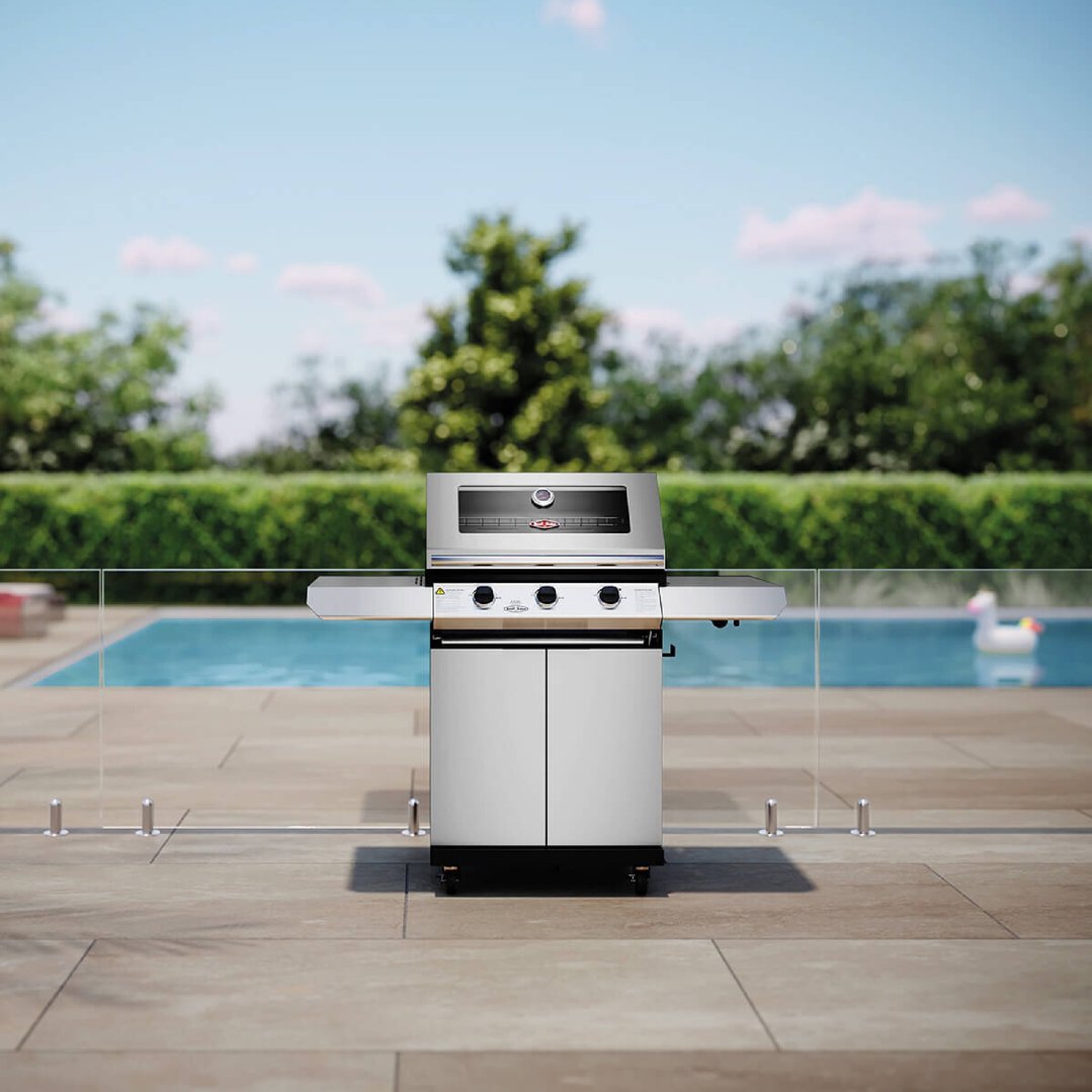 Stainless steel barbecue on a patio next to a swimming pool
