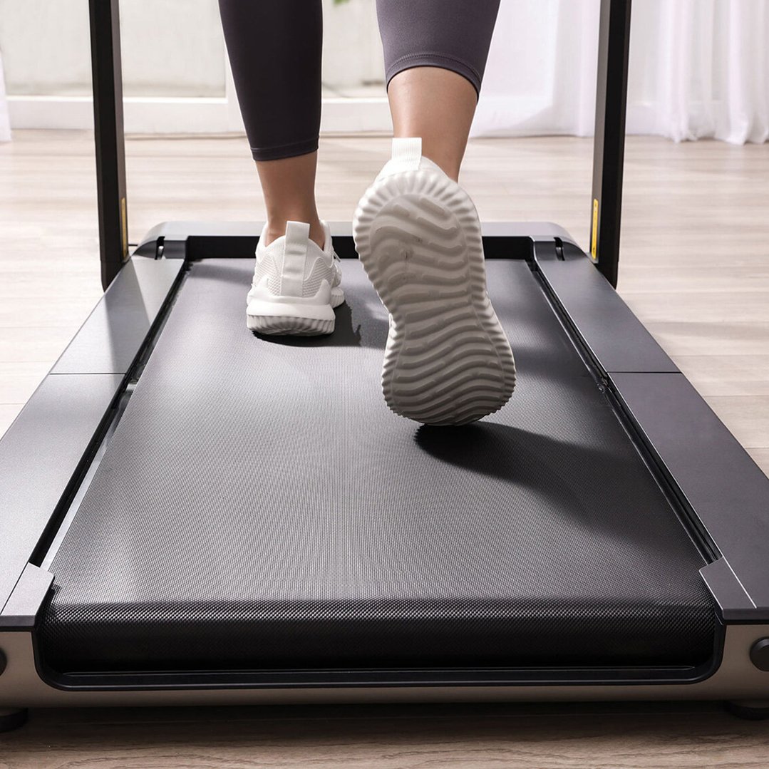 Person walking on a treadmill, viewed from behind, showing feet and legs